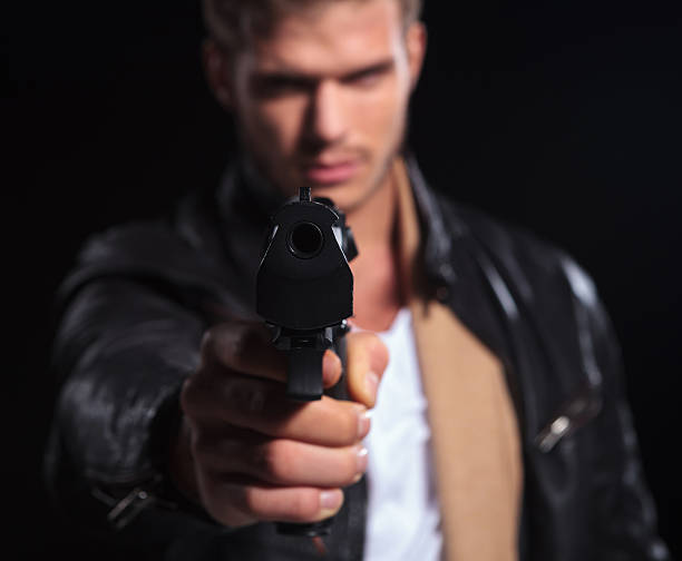 istock young assasin pointing his gun to the camera 481813875