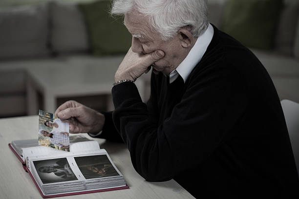 Widower remembering deceased wife Widower looking at the photos and remembering deceased wife mourner photos stock pictures, royalty-free photos & images