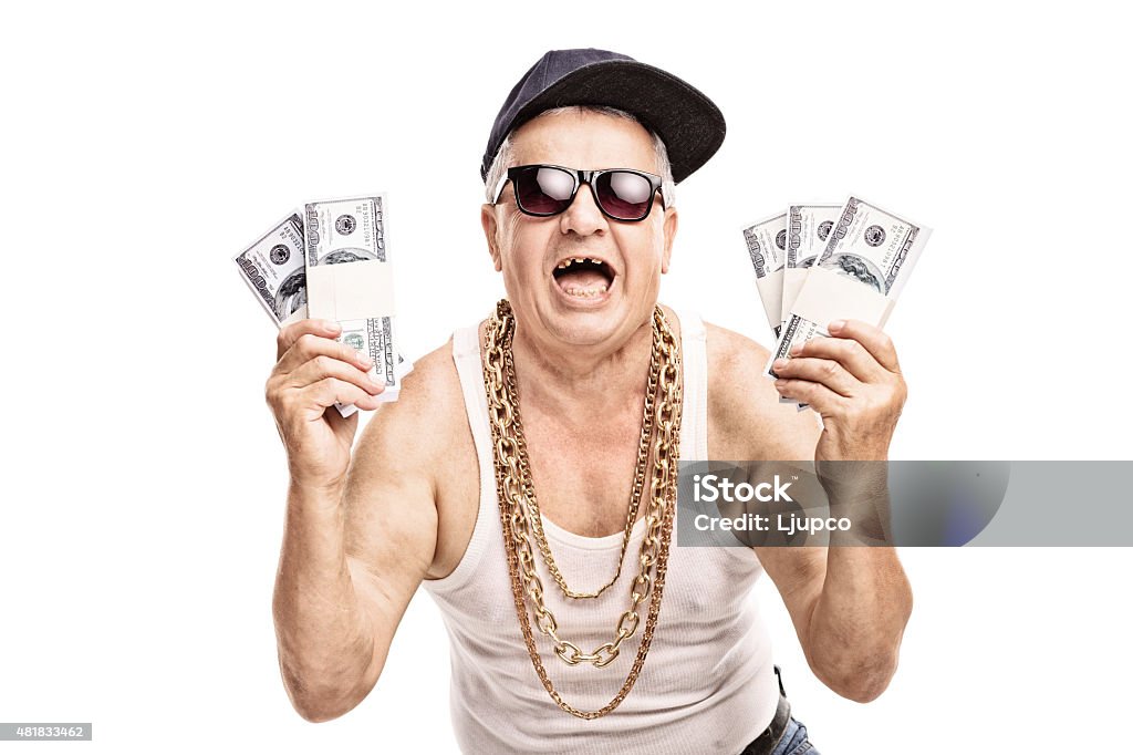 Senior in hip hop outfit holding few stacks of money Delighted senior in hip hop outfit holding a few stacks of money and looking at the camera isolated on white background Currency Stock Photo