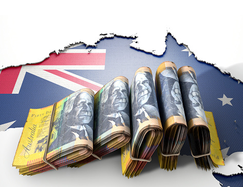 The shape of the country of Australia in the colours of its national flag recessed into an isolated white surface with a wad of folded Australian Dollar notes resting on it