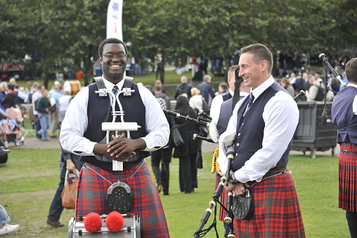 Glasgow, Scotland, UK - August 15, 2014: African drummer sharing a joke with fellow band mate at World bagpipe championships. African american/canadian drummer, glasgow, scotland. Looking towards camera smiling, to his left caucasian bandmate smiling and sharing a joke.
