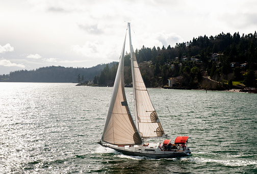 A sailboat cruises the Salish Sea near Bainbridge Island in the Puget Sound area of the Pacific Northwest, Washington State.