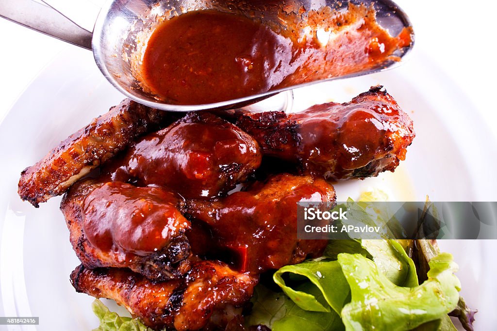 Chicken wings, sauce. A dish of chicken wings with sauce and greens. 2015 Stock Photo
