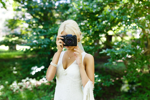 Beautiful bride with camera in a park