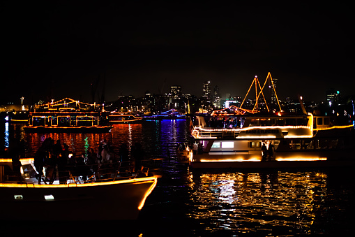 Sydney, Australia - January 1, 2015: Parade of Boats reflecting in Sydney bay after the midnight fireworks of the new years eve 2015, shot from a boat. city skyline in the background.