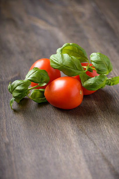 tomate e manjericão sobre uma mesa de madeira - phila imagens e fotografias de stock