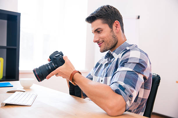 istock Happy man sitting at the table with photo camera 481849760