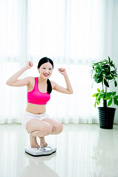 istock Happy woman on weighing scale 481857008