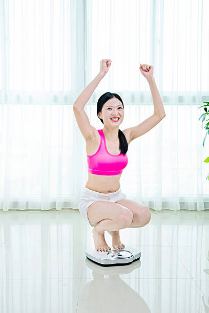 istock Happy woman on weighing scale 481857938