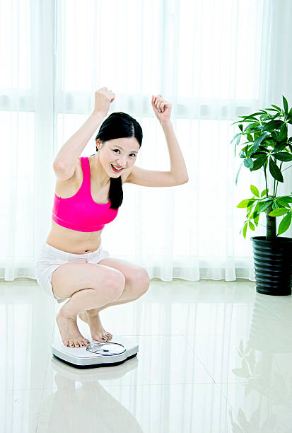 istock Happy woman on weighing scale 481857948