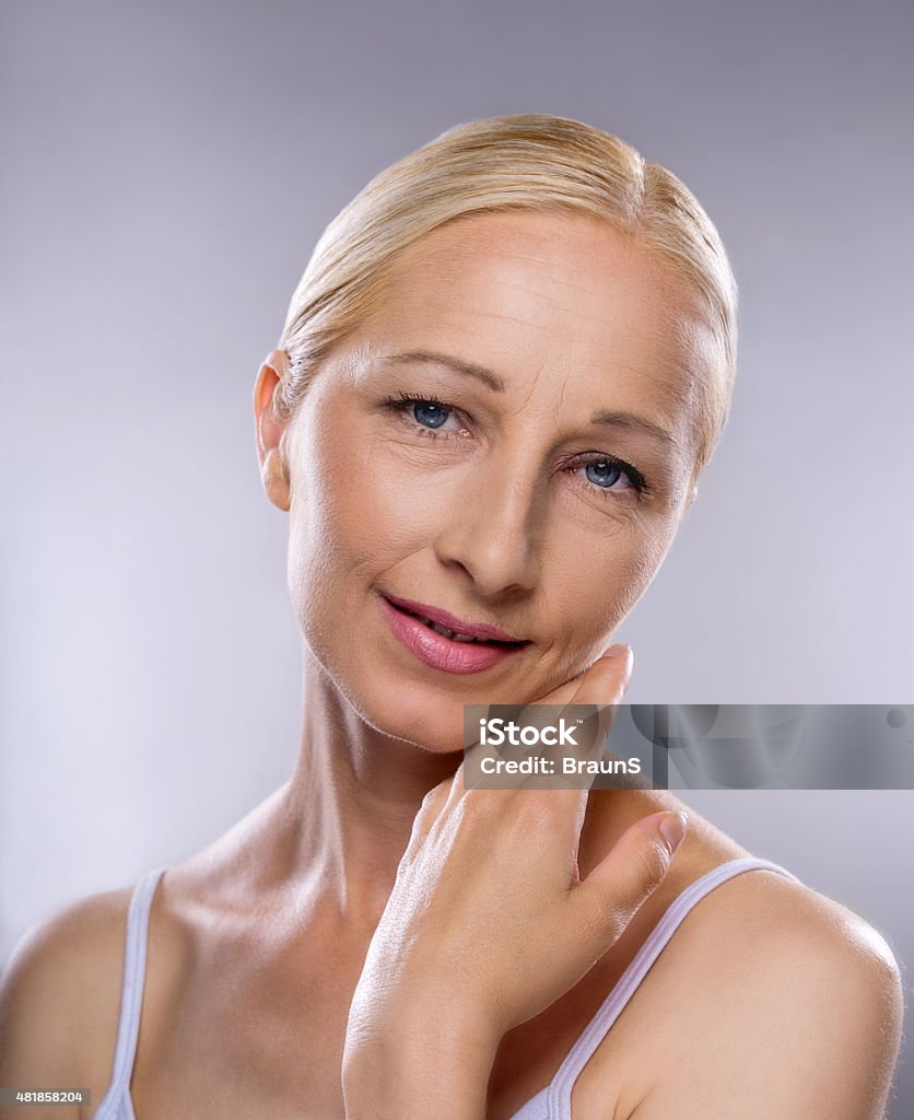 Smiling mature woman touching her soft skin. Beauty mature woman touching her face and looking at the camera. 2015 Stock Photo