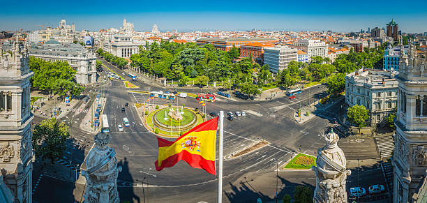 Madrid Plaza de Cibeles Spanish flag rooftop cityscape panorama Spain Spanish national flag flying proudly from the roof of the Palacio de Comunicaciones overlooking a panoramic vista across the busy Plaza de Cibeles towards the heart of central Madrid, Spain's vibrant capital city. ProPhoto RGB profile for maximum color fidelity and gamut. the flag of the madrid spain stock pictures, royalty-free photos & images