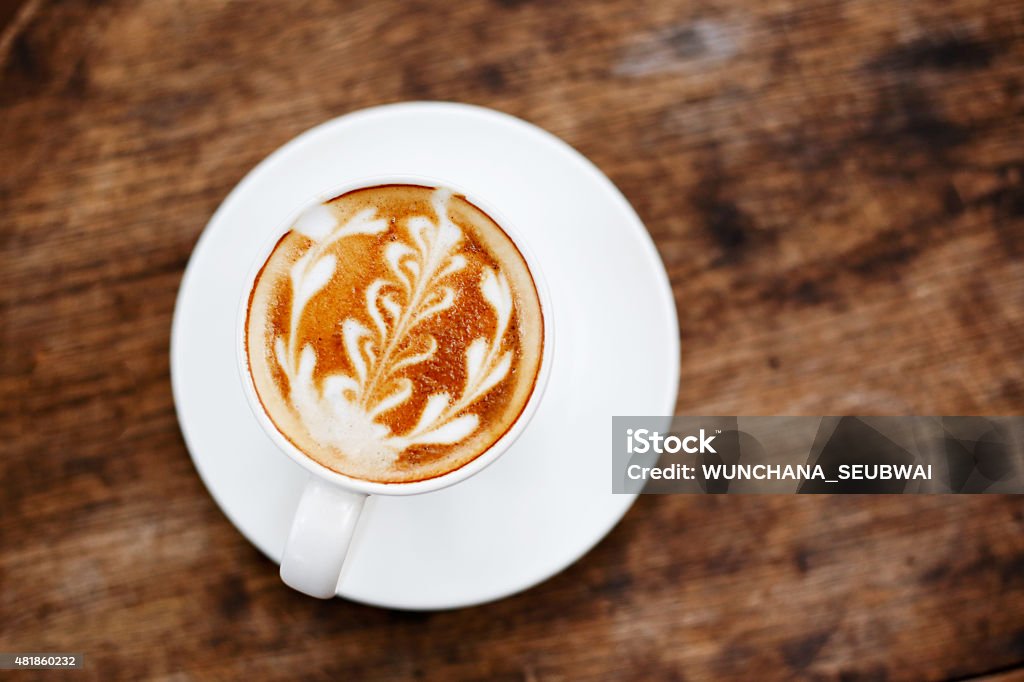 Cup of coffee with leaf pattern in a cup Cup of coffee with leaf pattern in a cup on wooden background 2015 Stock Photo