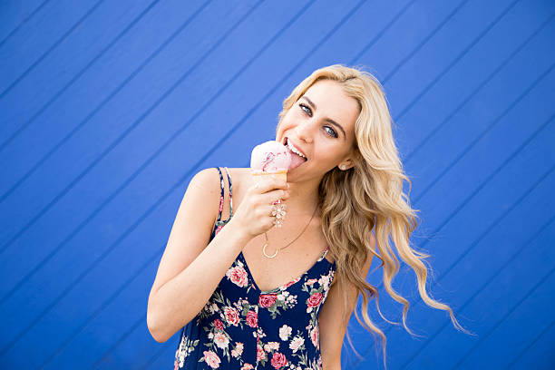 Ładna, młoda kobieta jest zabawa jedzenie lodów. – zdjęcie