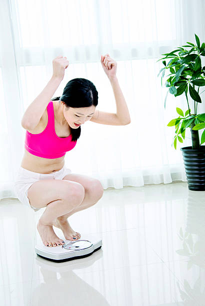 istock Happy woman on weighing scale 481869640