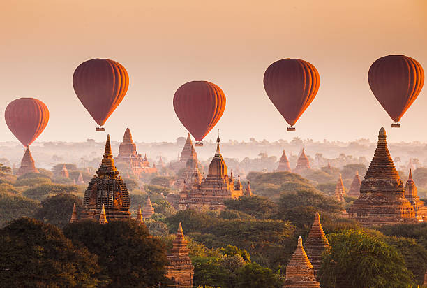 Balloon over plain of Bagan in misty morning, Myanmar Bagan is an archaeological zone of more than 2,000 ancient pagodas. It was built in 11th centuries during the rise of Bagan empire.Today Bagan is a part of Mandalay division, Myanmar. grassland in morning sunrise stock pictures, royalty-free photos & images