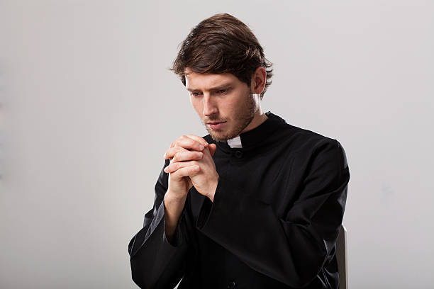 Priest is praying Young christian priest is saying a prayer god is love stock pictures, royalty-free photos & images