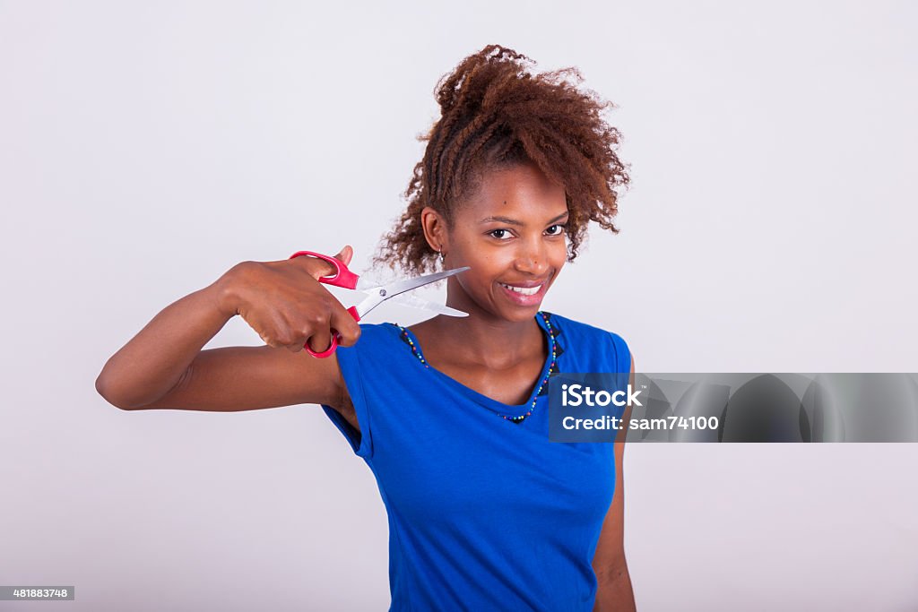 Young African American woman cutting her frizzy afro hair Young African American woman cutting her frizzy afro hair with scissors - Black people 2015 Stock Photo