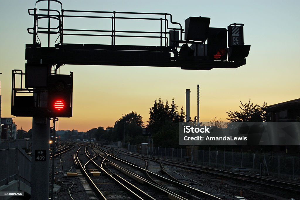 Railway signal at sunset A red stop signal next to railway lines heading West at sunset.  Basingstoke railway station, Hampshire, UK. Railway Signal Stock Photo