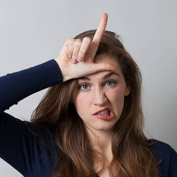 istock angry 20's woman making a L loser hand gesture 481886150
