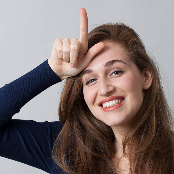 istock beautiful 20s girl smiling with L sign on forehead 481886174