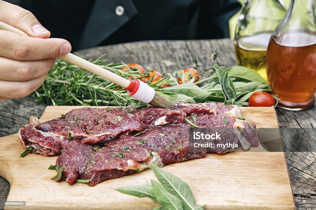 Cooking ingredients Cooking ingredients: marinated meat,oil,vinegar, herbs and vegetables. Chef is carving and marinating meat. Marinated Stock Photo