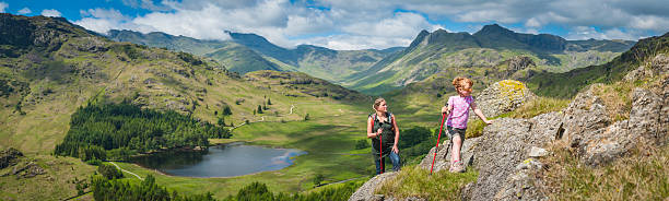 Active mother and daughter hiking in idyllic mountain scenery panorama