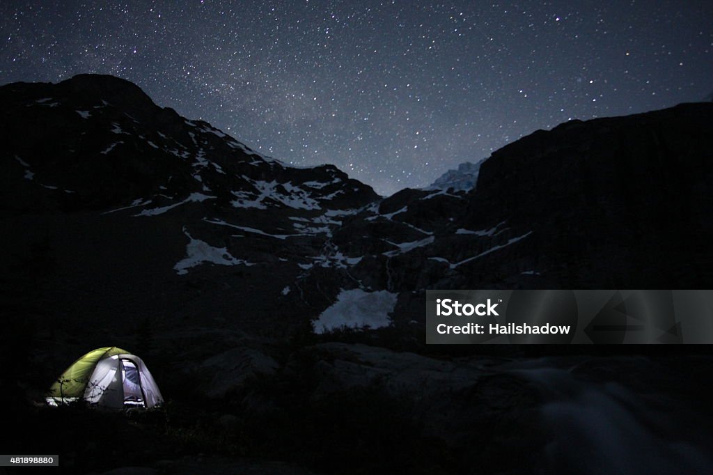Tent under a star-lit sky Camping tent under a snow and ice covered mountains and night sky dotted with bright stars. 2015 Stock Photo