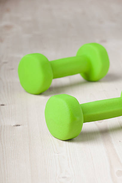 istock small green dumbbells on wooden surface 481913411