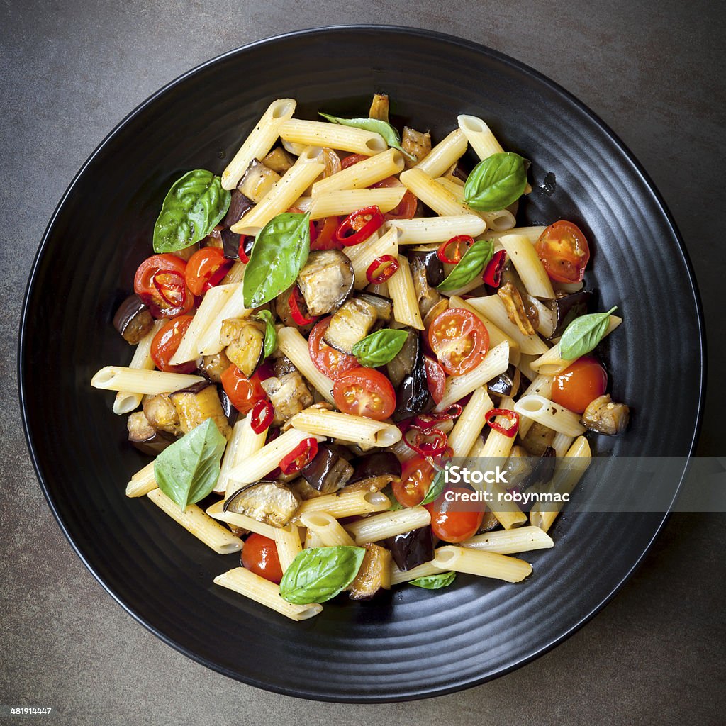 Eggplant Chilli and Tomato Pasta Eggplant, chilli and tomato penne pasta, on a black serving platter.  Garnished with basil.Eggplant, chilli and tomato penne pasta, on a black serving platter.  Garnished with basil. Pasta Stock Photo