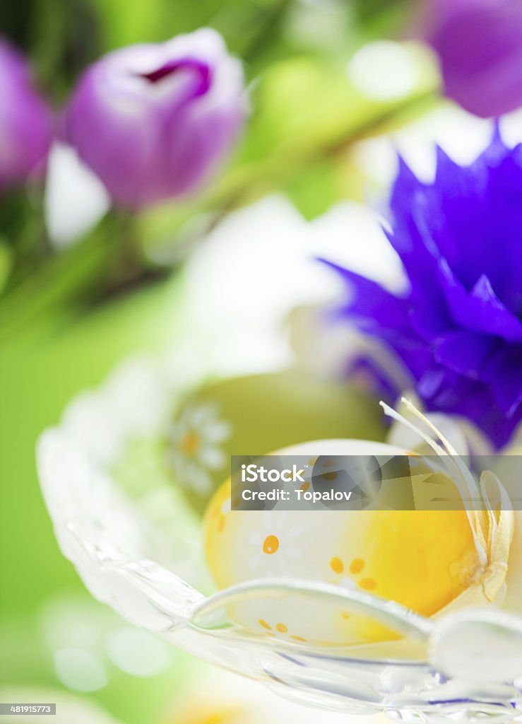 Yellow Easter Egg Easter eggs in glass bowl with tulip flowers in background Animal Egg Stock Photo