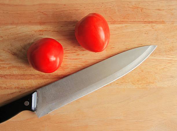 istock Close up knife and tomato on wooden table 481926108