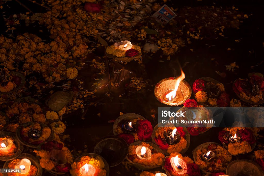 Religious offerings on River ganges and oil lamps, Varanasi, India Religious offering to holy Ganges river after sunset. As an offering, diya or oil lamps are put on small boats made of leaves and set afloat on the water.  Hinduism Stock Photo