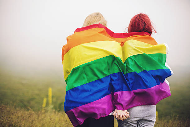 pelirrojo mujer rubia y envueltos en bandera del arco iris - gay pride flag fotografías e imágenes de stock