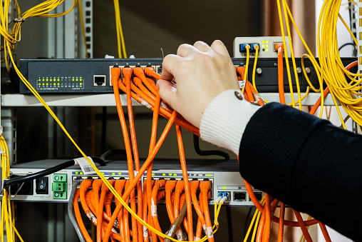 woman connecting network cables to switches