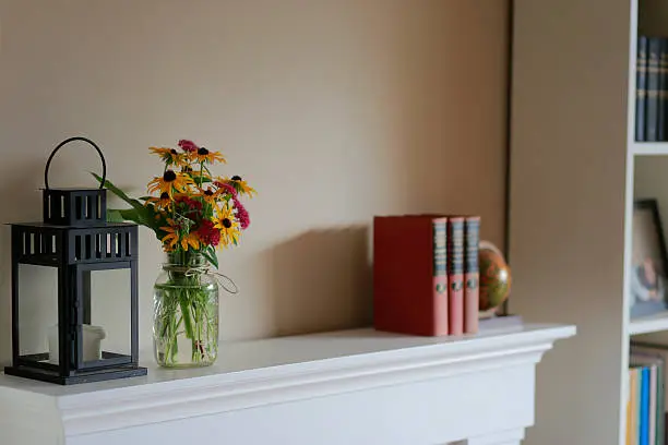 Photo of flowers in a vase next to a lantern on top of a mantle indoors