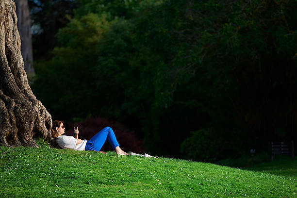 jeune fille lecture et allongée sur l'arbre et terrain - women grass glasses e reader photos et images de collection