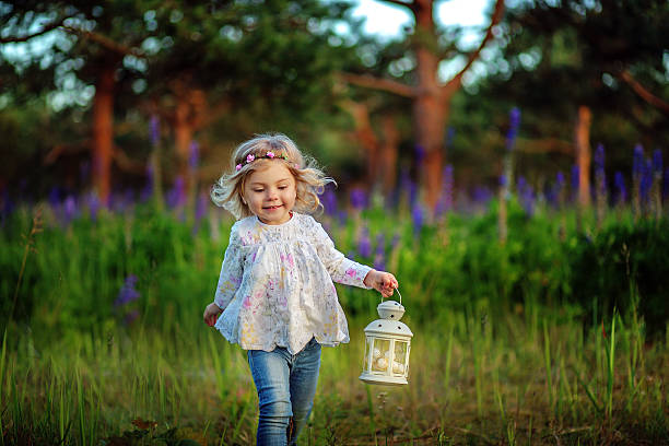 Beautiful little girl with blue flowers on the field. Sunshine. Blonde hair. Artistic intent ,added noise.