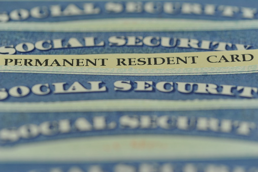 American Green Card (US Permanent Resident) hidden in a stack of Social Security cards. Selective Focus