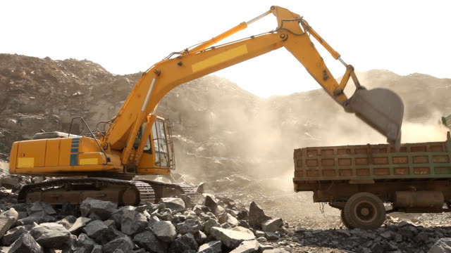 Bulldozer working at mining site loading stone on a truck