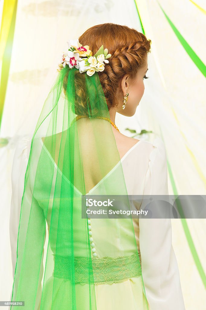 Bridal hairstyle Back view of beautiful young woman in dress with braided hairstyle, flowers and green veil in hair. Modern bride. 2015 Stock Photo