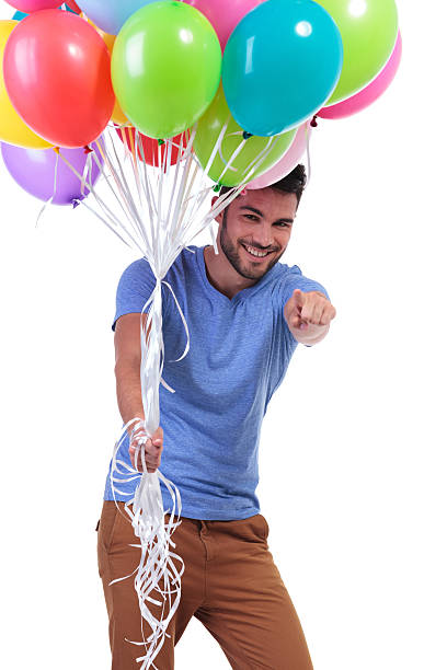 istock man holding balloons and pointing to the camera 481958979