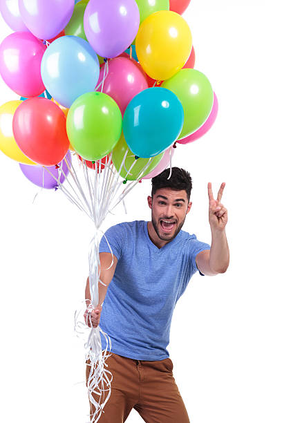 istock man holding a bunch of baloons and making victory sign 481958981