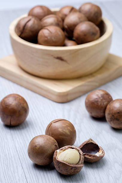 istock Macadamia in wooden bowl on white wooden table 481963484