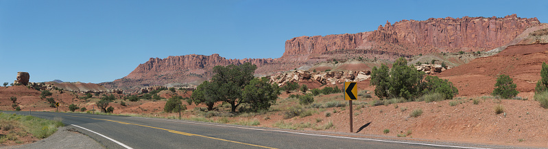 Arizona desert road panoramic view in a sunny day with red rock mountain range in background with arrow turn road sign