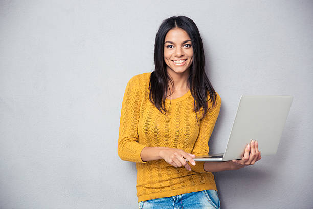istock Happy young woman holding laptop 481965472
