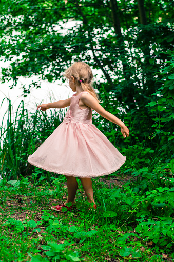 little blond girl with long hair dancing in meadow
