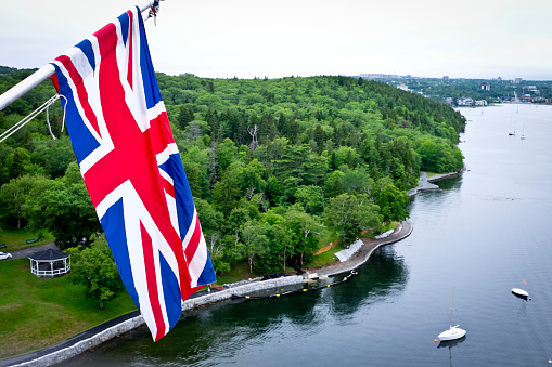 The British flag the Union Jack flys over Halifax Nova Scotia's Northwest Arm.  Overcast sky, green forest and blue water.  Aerial view from the Sir Sanford Flemming tower.