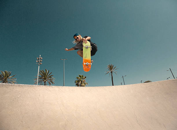 Young man jumping with skateboard Young man skating in skatepark skateboard tricks stock pictures, royalty-free photos & images