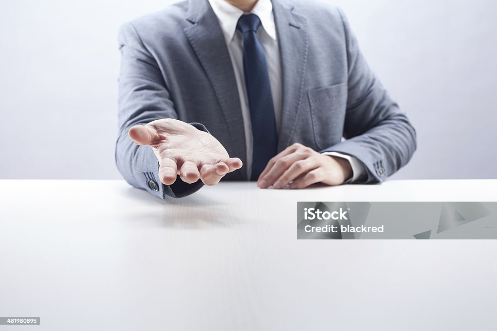 Businessman Open Hand Businessman showing an open hand at desk. Front View Stock Photo